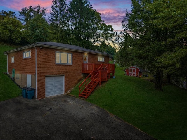 view of front of home with a lawn, a deck, a garage, and a shed