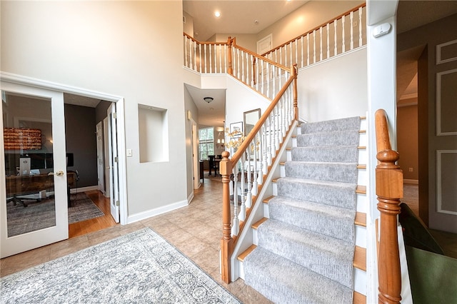 stairway featuring french doors, hardwood / wood-style floors, and a high ceiling