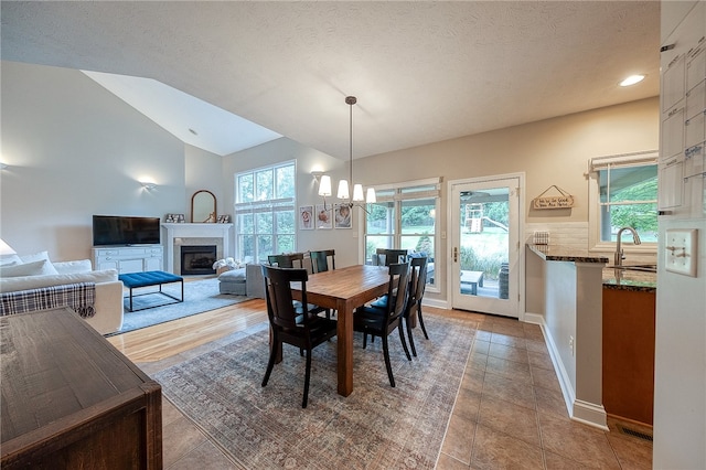 dining space with a textured ceiling, hardwood / wood-style flooring, lofted ceiling, and plenty of natural light