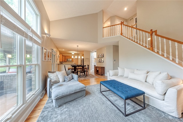 living room featuring an inviting chandelier, light wood-type flooring, and high vaulted ceiling