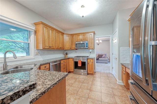 kitchen with a textured ceiling, sink, stainless steel appliances, and tasteful backsplash