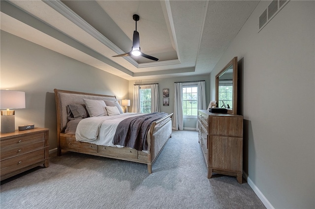 carpeted bedroom featuring ceiling fan and a raised ceiling