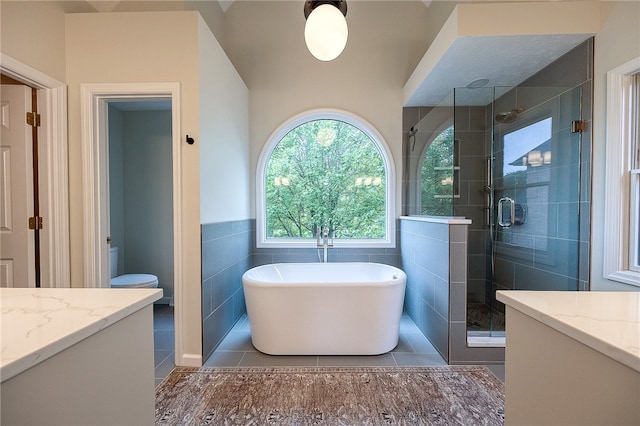 full bathroom with tile walls, vanity, plus walk in shower, toilet, and tile patterned floors