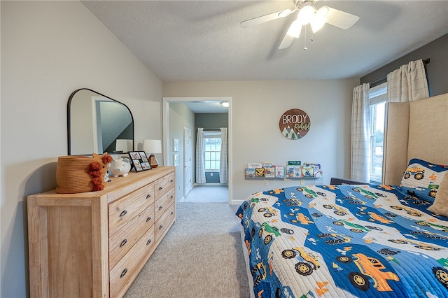 bedroom with light carpet, multiple windows, ceiling fan, and a textured ceiling