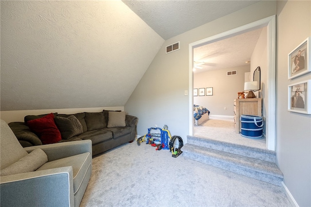 living room featuring ceiling fan, vaulted ceiling, a textured ceiling, and carpet flooring