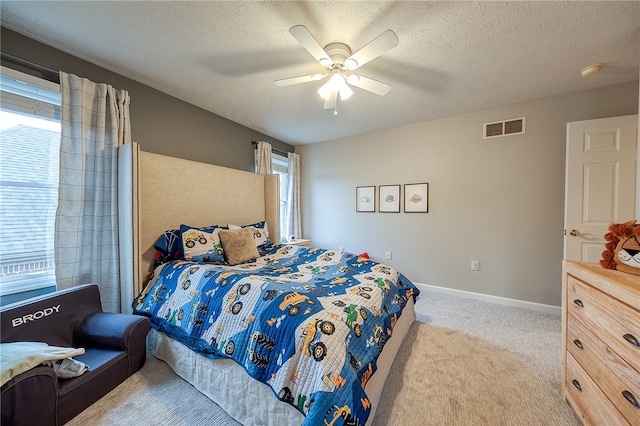 carpeted bedroom featuring multiple windows, a textured ceiling, and ceiling fan