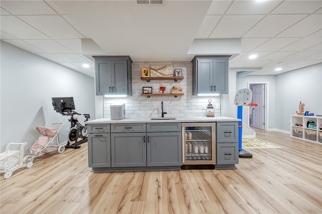 bar featuring wine cooler, sink, and gray cabinetry