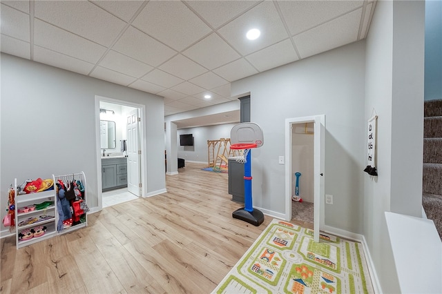 game room with light hardwood / wood-style floors and a paneled ceiling