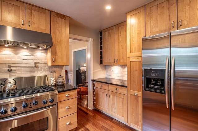 kitchen with decorative backsplash, stainless steel appliances, dark hardwood / wood-style floors, and dark stone counters