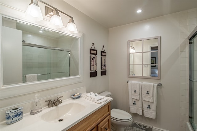 bathroom featuring vanity, a shower with shower door, and toilet