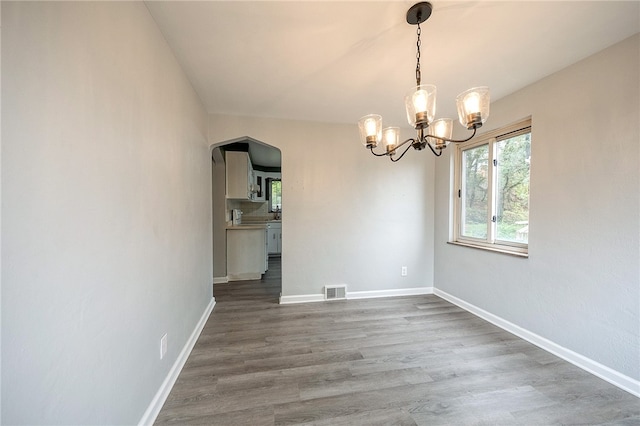 unfurnished dining area with a notable chandelier and hardwood / wood-style floors