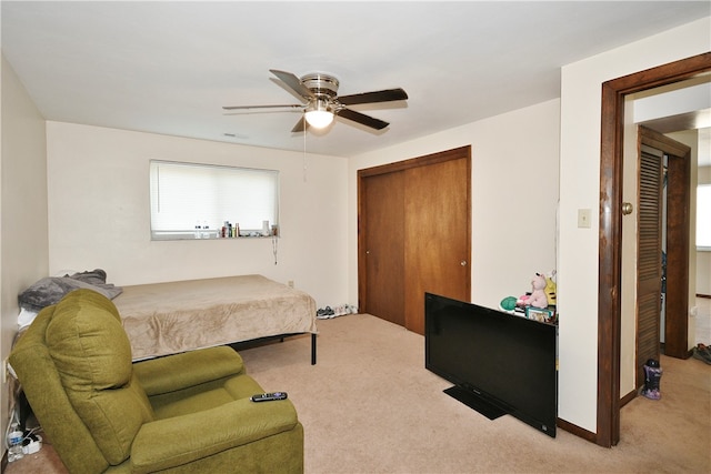 bedroom featuring light carpet, ceiling fan, and a closet