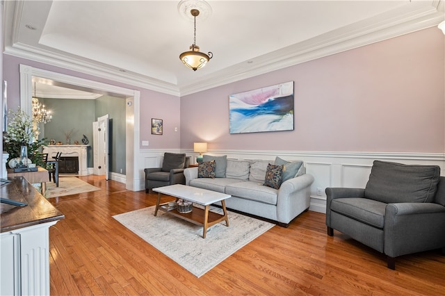 living room featuring ornamental molding, a fireplace, wood-type flooring, and a tray ceiling