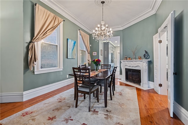 dining room with a notable chandelier, ornamental molding, and light hardwood / wood-style flooring