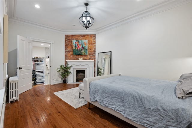 bedroom with wood-type flooring, crown molding, a notable chandelier, and radiator