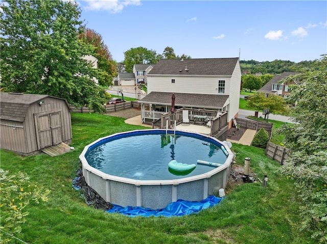 view of swimming pool with a shed, a lawn, and a wooden deck