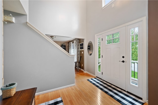 foyer entrance with a towering ceiling and light hardwood / wood-style floors