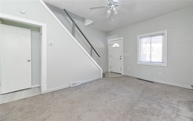 foyer with ceiling fan and light carpet