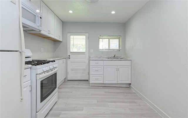 kitchen with white cabinets, white appliances, light hardwood / wood-style flooring, and sink