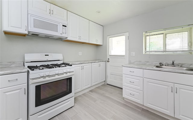 kitchen with light stone countertops, light wood-type flooring, white appliances, sink, and white cabinets