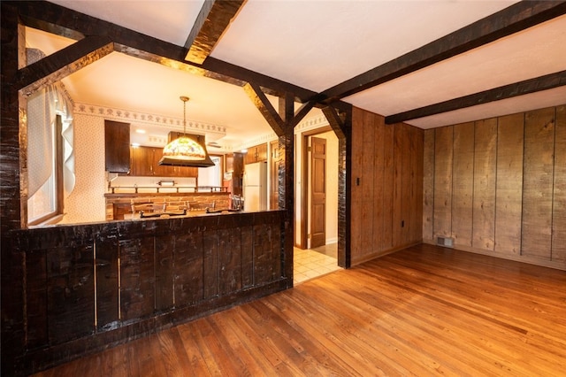 bar with light hardwood / wood-style floors, wood walls, beamed ceiling, and white refrigerator