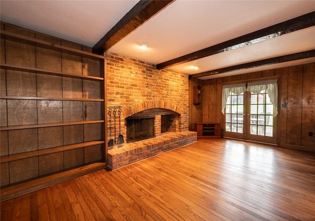 unfurnished living room featuring wooden walls, a fireplace, and hardwood / wood-style floors