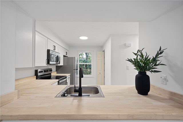 kitchen with stainless steel appliances, white cabinetry, kitchen peninsula, and sink