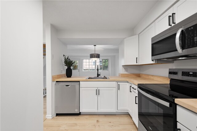 kitchen with sink, decorative light fixtures, light hardwood / wood-style flooring, white cabinetry, and stainless steel appliances