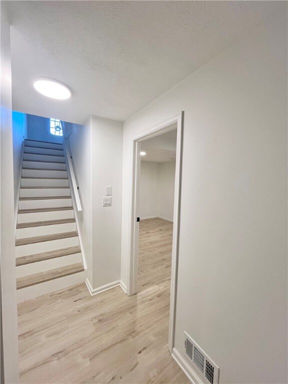 stairs with a textured ceiling and hardwood / wood-style flooring