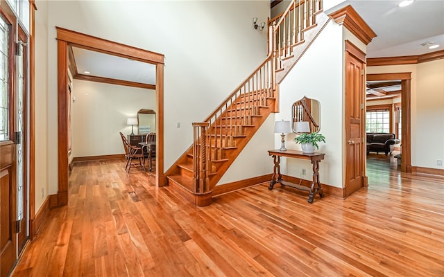 stairs with hardwood / wood-style flooring and crown molding