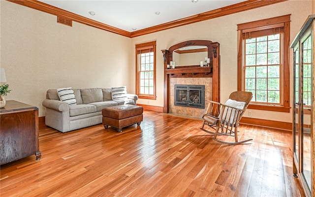 living room with a tile fireplace, crown molding, and light hardwood / wood-style floors