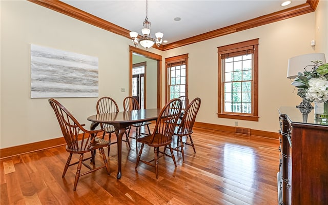 dining room with ornamental molding, an inviting chandelier, and hardwood / wood-style floors