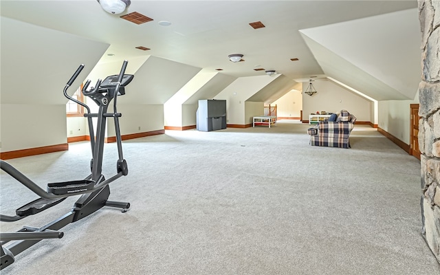 exercise area with vaulted ceiling and light carpet