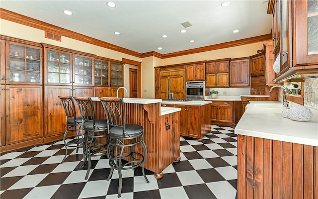 kitchen with sink, tasteful backsplash, a kitchen island with sink, paneled fridge, and crown molding