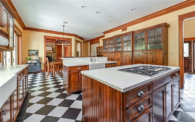 kitchen with stainless steel gas cooktop, pendant lighting, crown molding, a center island, and sink