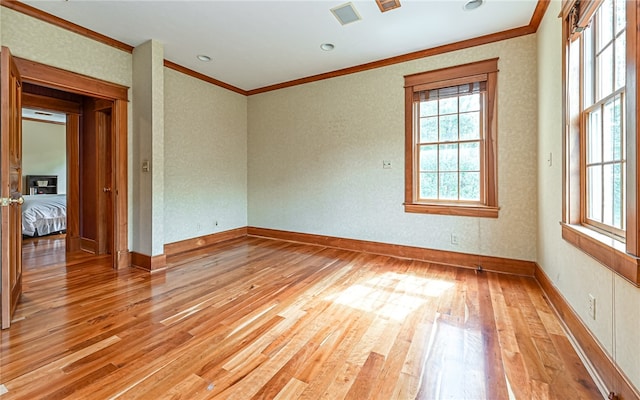 empty room with light hardwood / wood-style flooring and crown molding