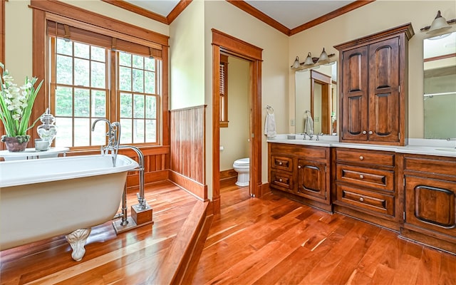 bathroom with vanity, ornamental molding, a tub, wood-type flooring, and toilet