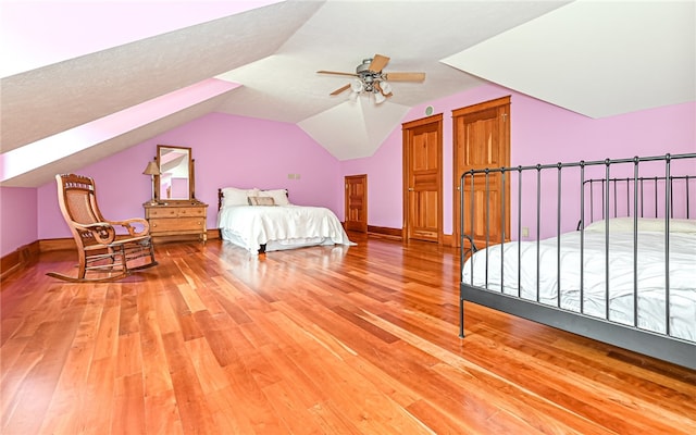 bedroom with a textured ceiling, wood-type flooring, vaulted ceiling, and ceiling fan