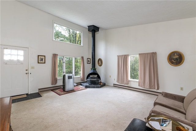 carpeted living room with a textured ceiling, baseboard heating, a towering ceiling, and a wood stove