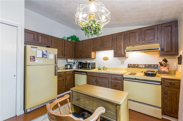 kitchen featuring hanging light fixtures, vaulted ceiling, white appliances, a textured ceiling, and sink