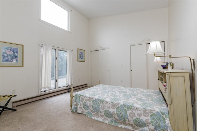 bedroom featuring a high ceiling, carpet flooring, and a baseboard heating unit