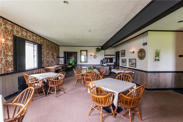 carpeted dining space featuring a textured ceiling and wooden walls