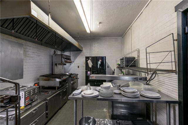 kitchen featuring brick wall, black fridge, a textured ceiling, and high end range