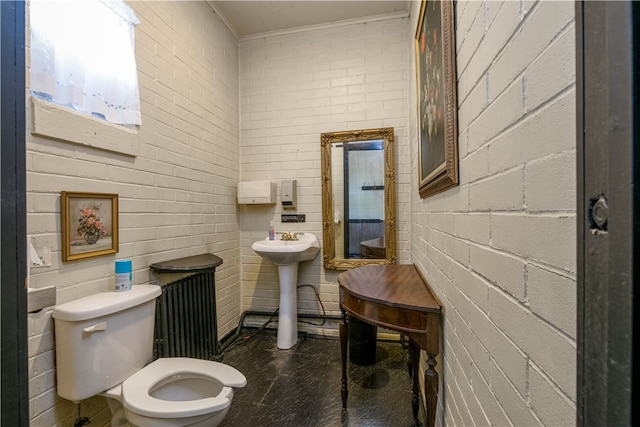 bathroom featuring ornamental molding, brick wall, sink, and toilet