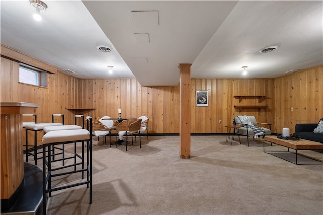 interior space featuring carpet floors, bar, and wood walls