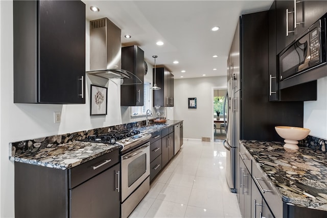 kitchen with light tile patterned floors, sink, wall chimney range hood, stainless steel appliances, and dark stone counters