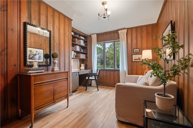 home office featuring light wood-type flooring, a chandelier, and wooden walls