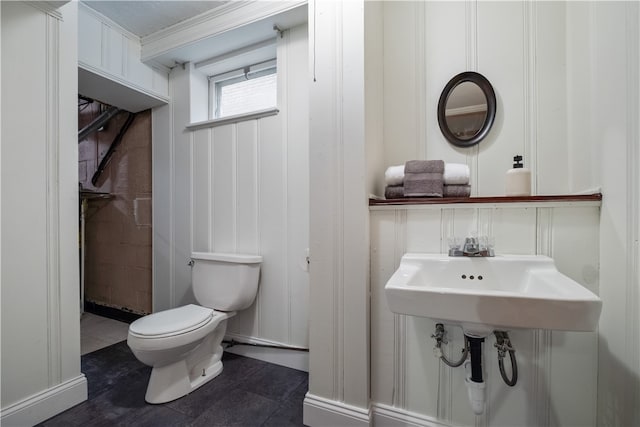 bathroom with tile patterned flooring, crown molding, and toilet