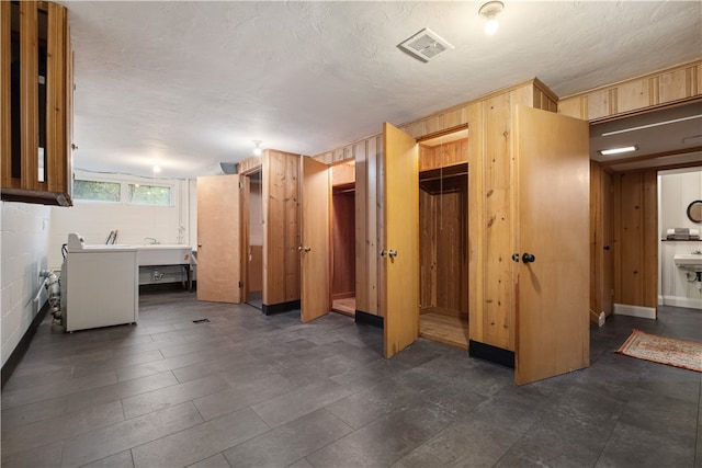 interior space featuring a textured ceiling, a closet, wood walls, and a spacious closet