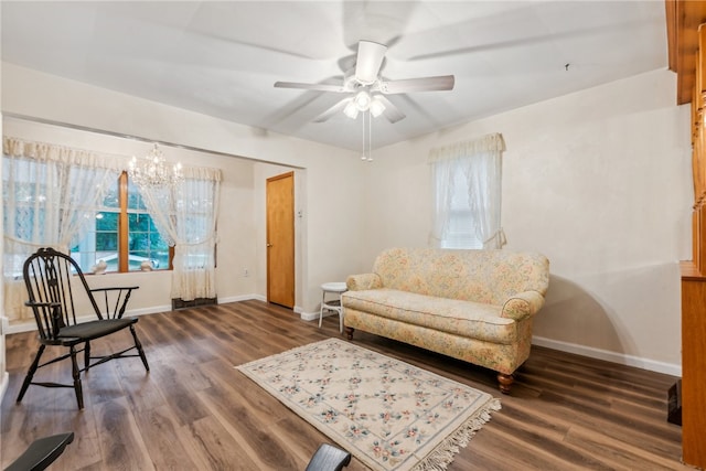 sitting room with dark wood-type flooring and ceiling fan with notable chandelier